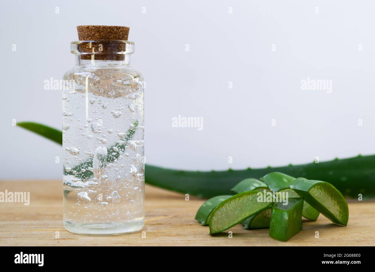 Glasflasche mit Aloe Vera Gel mit ganzen Blättern und Pflanzenstücken auf  Holzgrund Stockfotografie - Alamy