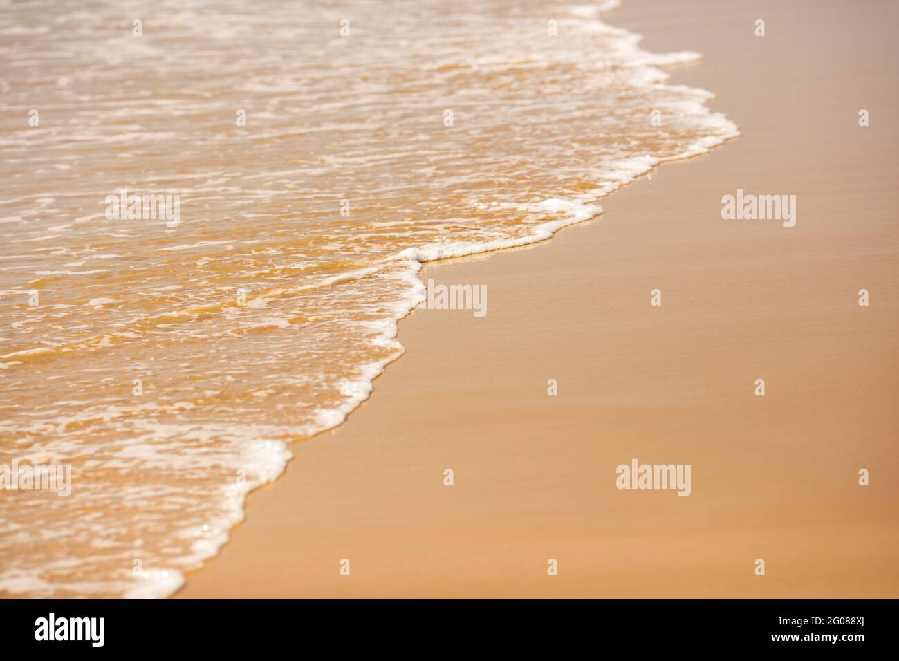 Nahaufnahme von hellen, schäumenden Wellen am Sandstrand Stockfoto