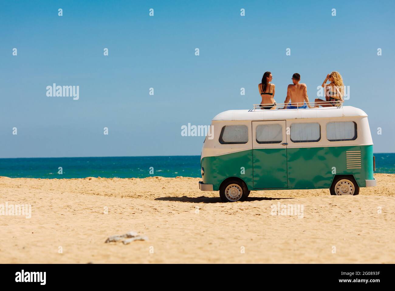 Eine Gruppe von drei Freunden genießt sonnige Tage auf einem Hippie-Auto Stockfoto