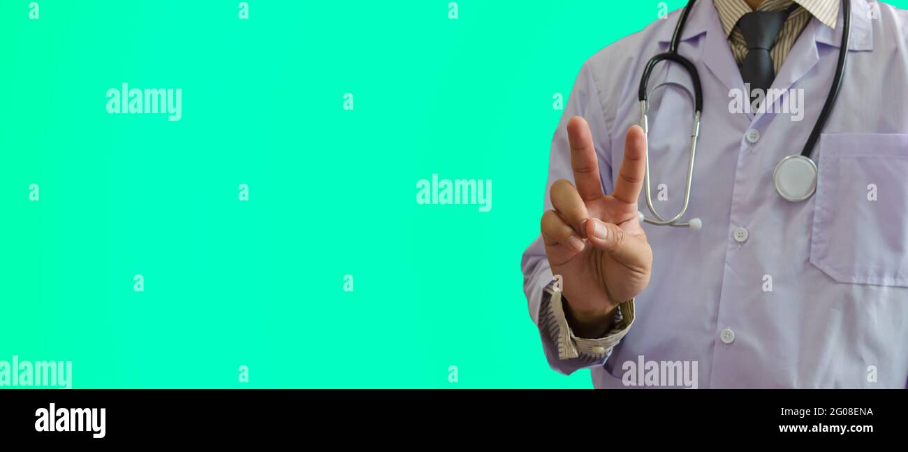 Der Arzt hielt ein zwei-Finger-Symbol auf grünem Hintergrund. Ermutigen Sie den Patienten und den Arzt, schwere Krankheiten gemeinsam zu behandeln. Stockfoto