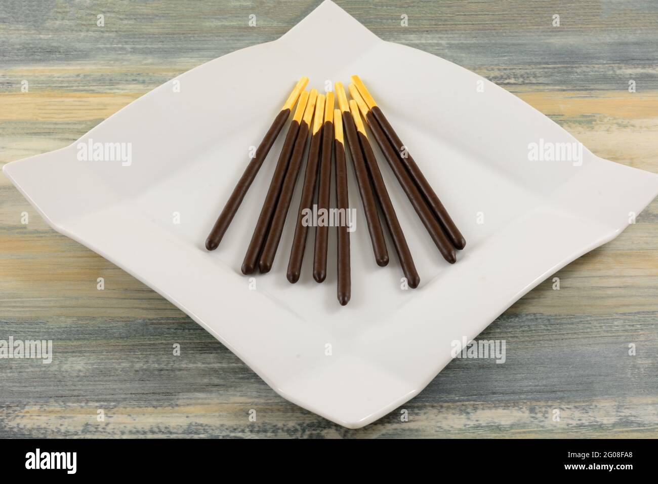 Biscuit-Sticks mit Schokoladencreme auf weißem Snackteller auf dem Tisch Stockfoto