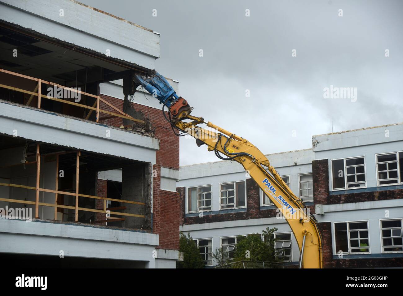 GREYMOUTH, NEUSEELAND, 19. Januar 2021: Ein Bagger nutzt einen Klauenaufsatz, um das alte Krankenhausgebäude in Greymouth, Neuseeland, im Januar abzureißen Stockfoto