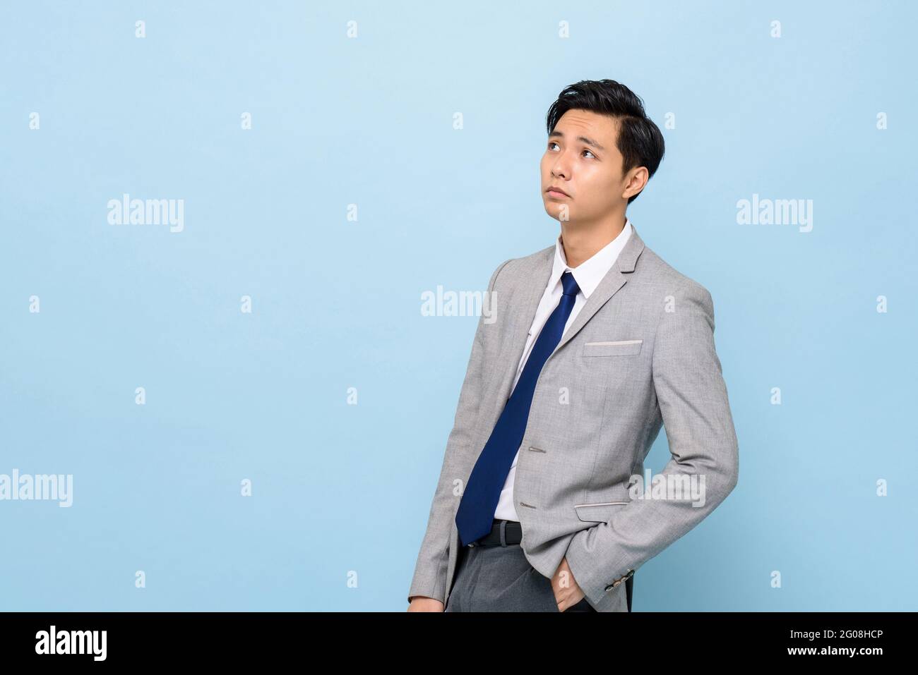 Gelangweilter Asiatischer Geschaftsmann Der Im Abgeschiedenen Hellen Blues Studio Hintergrund Denkt Und Aufschaut Um Platz Beiseite Zu Kopieren Stockfotografie Alamy