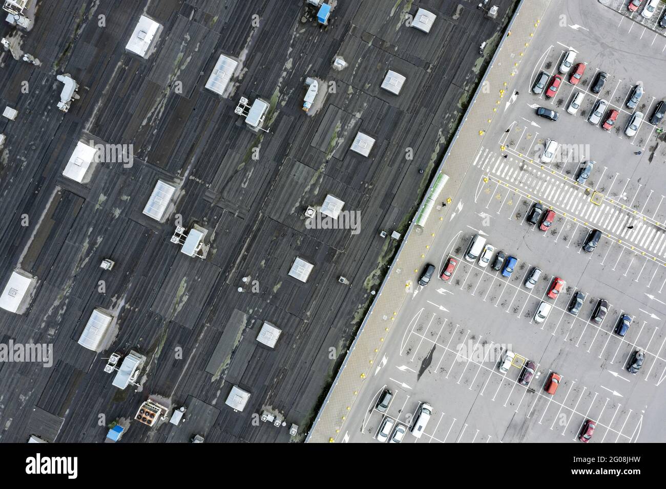 Abstrakte Luftaufnahme des Supermarktdachs und des Parkplatzes mit geparkten Autos Stockfoto