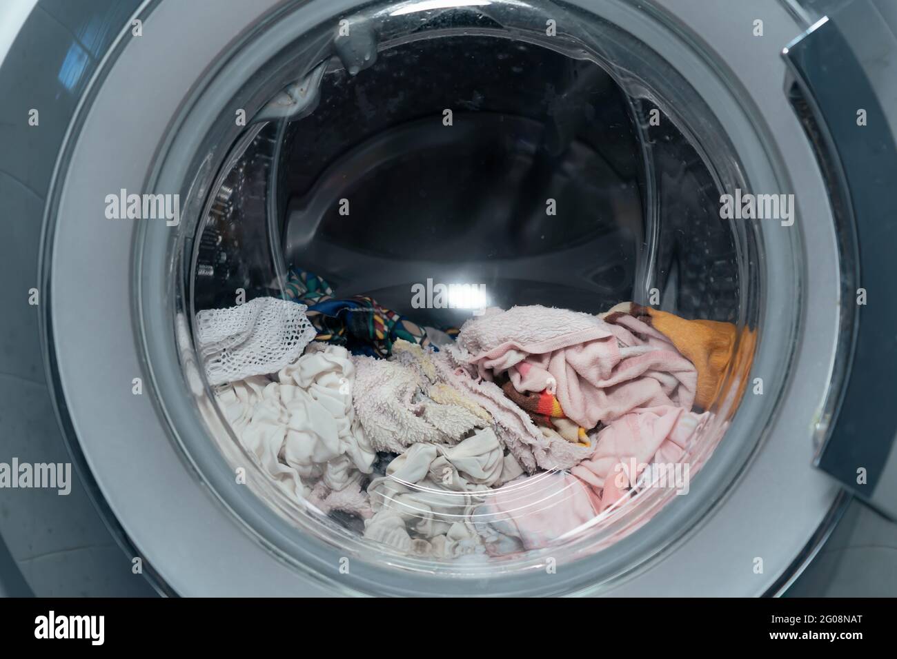 Frontlader-Waschmaschine mit nasser Kleidung und Handtuch darin Stockfoto