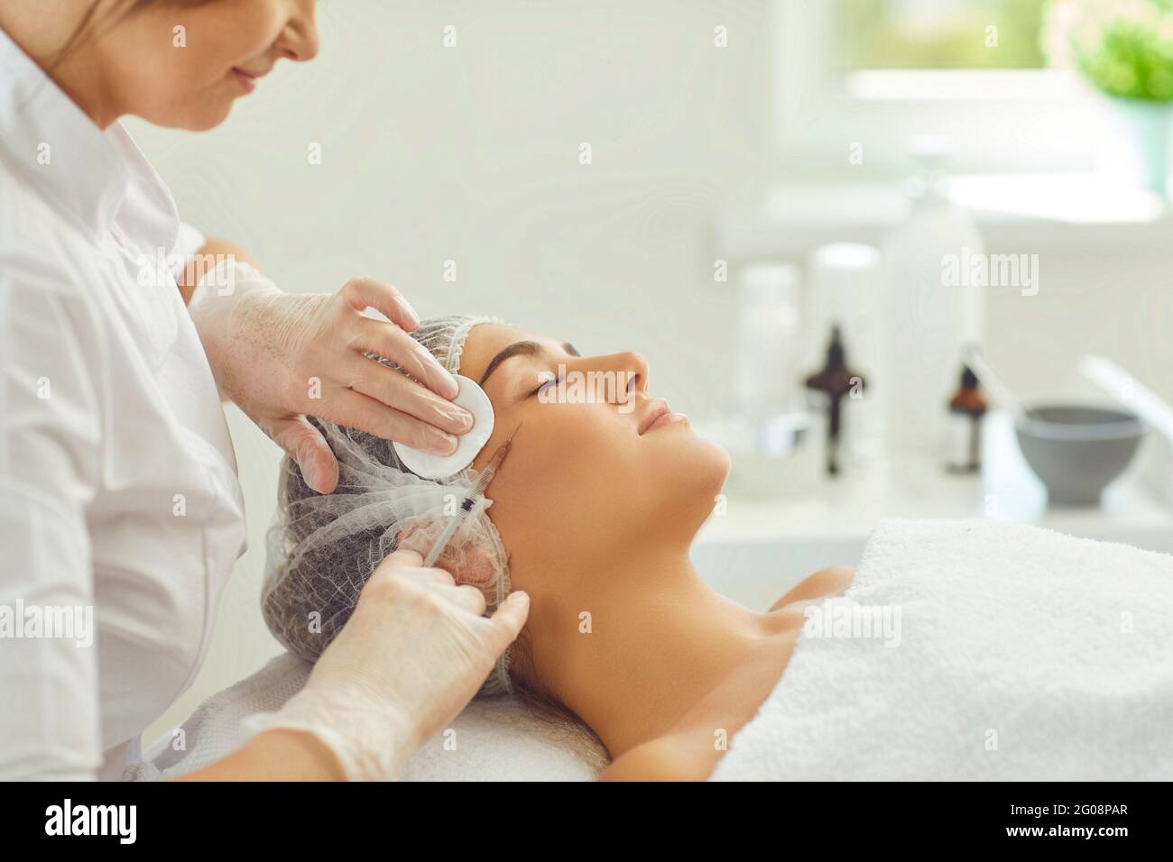 Lächelnde Frau bekommt Schönheit Botox Anti-Aging-Haut Injektion auf die Wange von professionellen Dermatologen Stockfoto