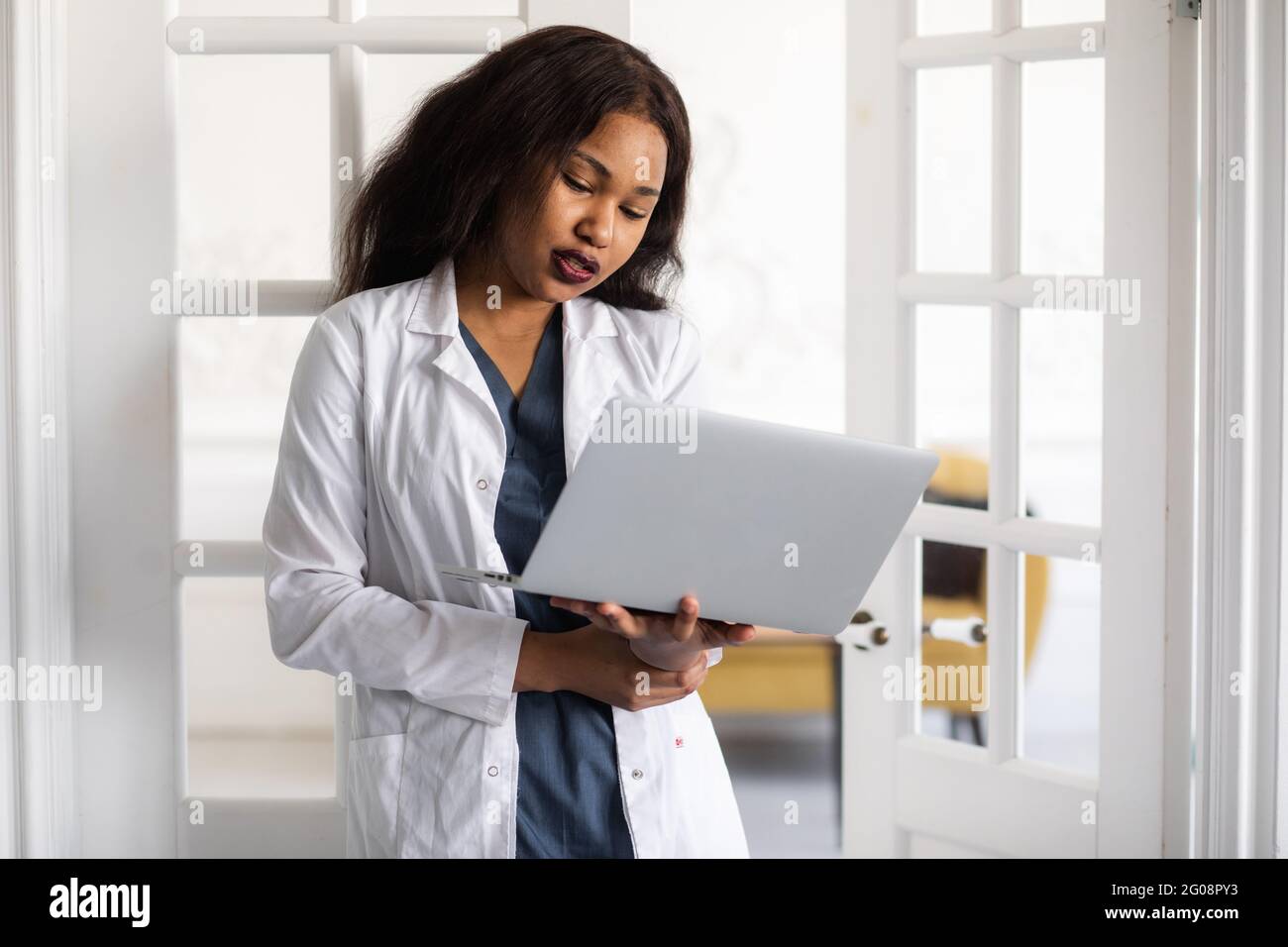 Gutaussehende, zufriedene afroamerikanische Ärztin, die an einem Laptop arbeitet. Telemedizin Stockfoto