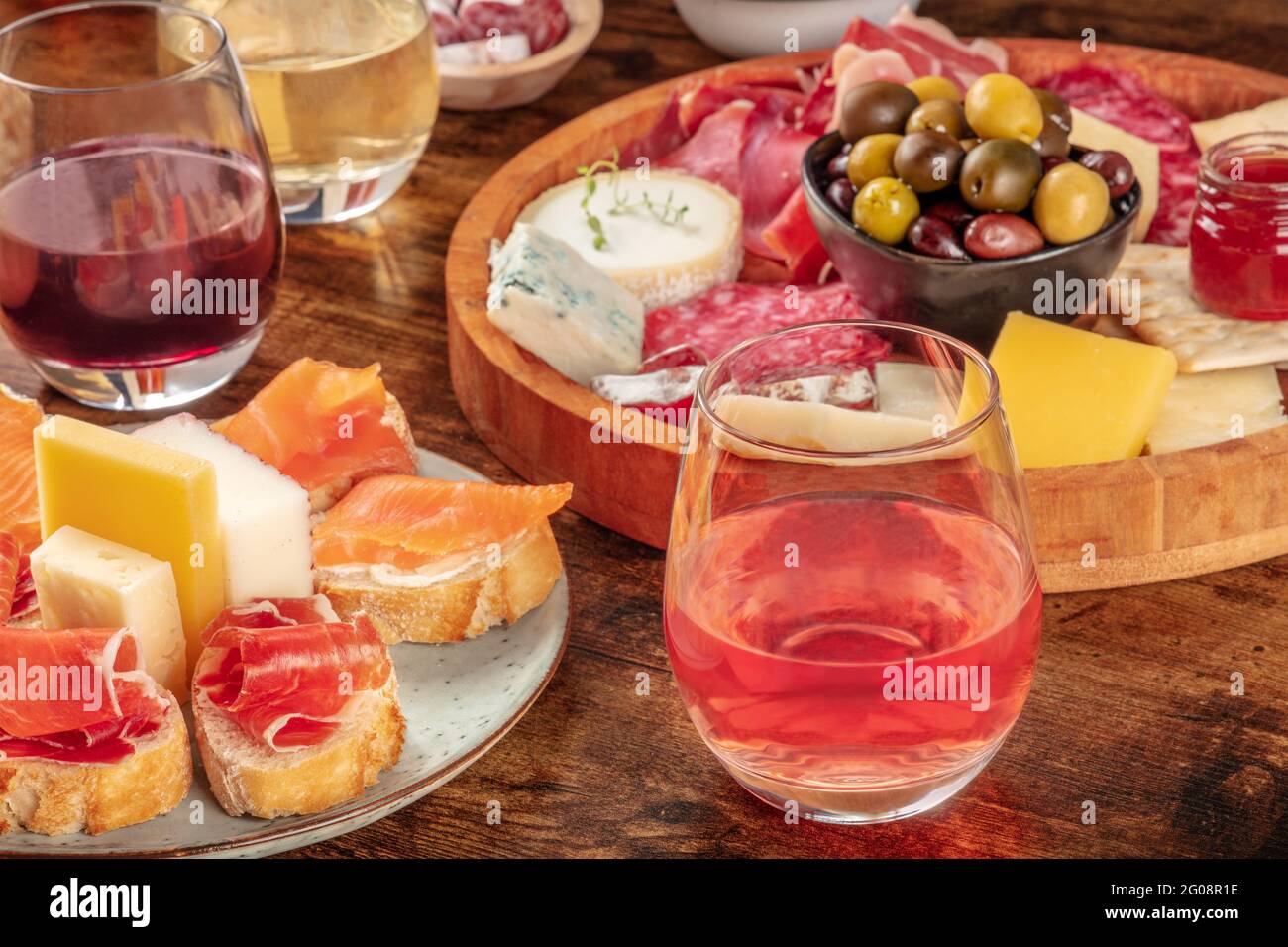 Wein, Sandwiches, Wurstwaren und Käseplatte auf rustikalem Holzhintergrund. Spanische Tapas oder italienische Antipasti auf einem Tisch in einer Bar Stockfoto