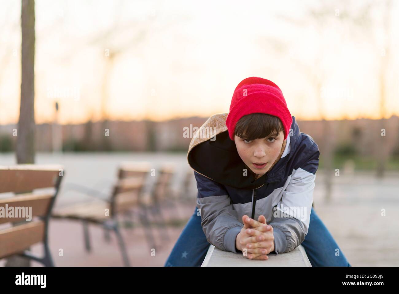 Stilvoller Teenager, der auf einem Zaun in einem Stadtpark sitzt Stockfoto