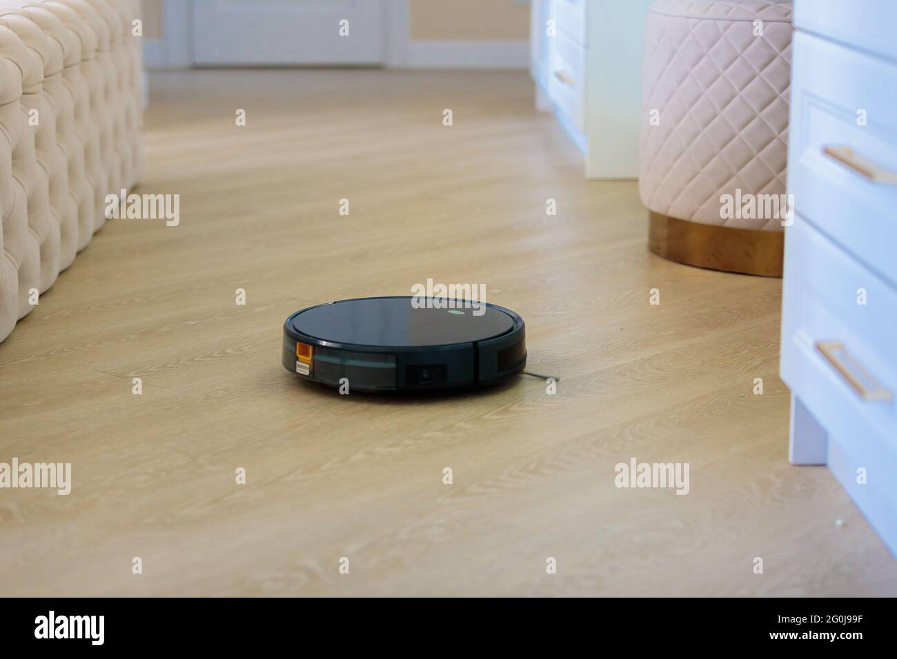 Der kreisförmige Roboter-Staubsauger sammelt Rückstände vom Boden des  Wohnzimmers. Schwarze Farbe Stockfotografie - Alamy
