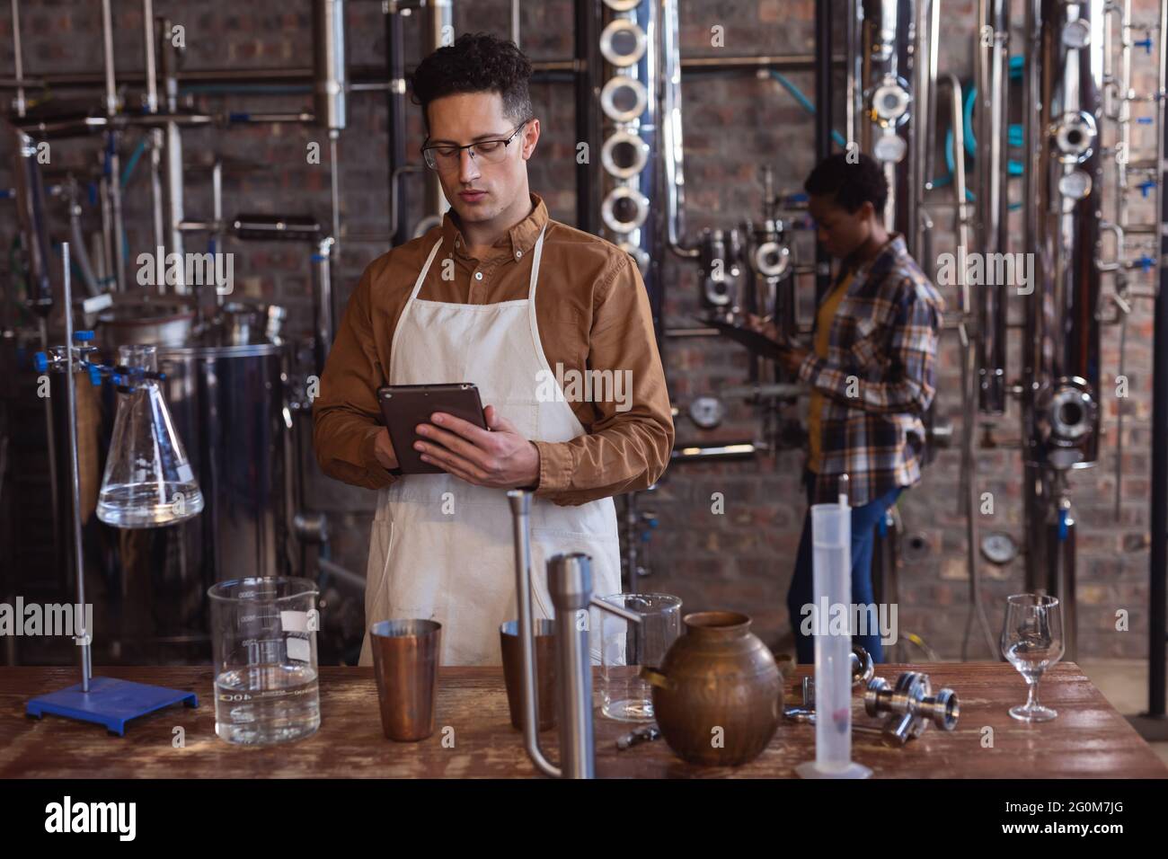 Kaukasischer Arbeiter mit Schürze und digitalem Tablet in der Gin Distillery Stockfoto