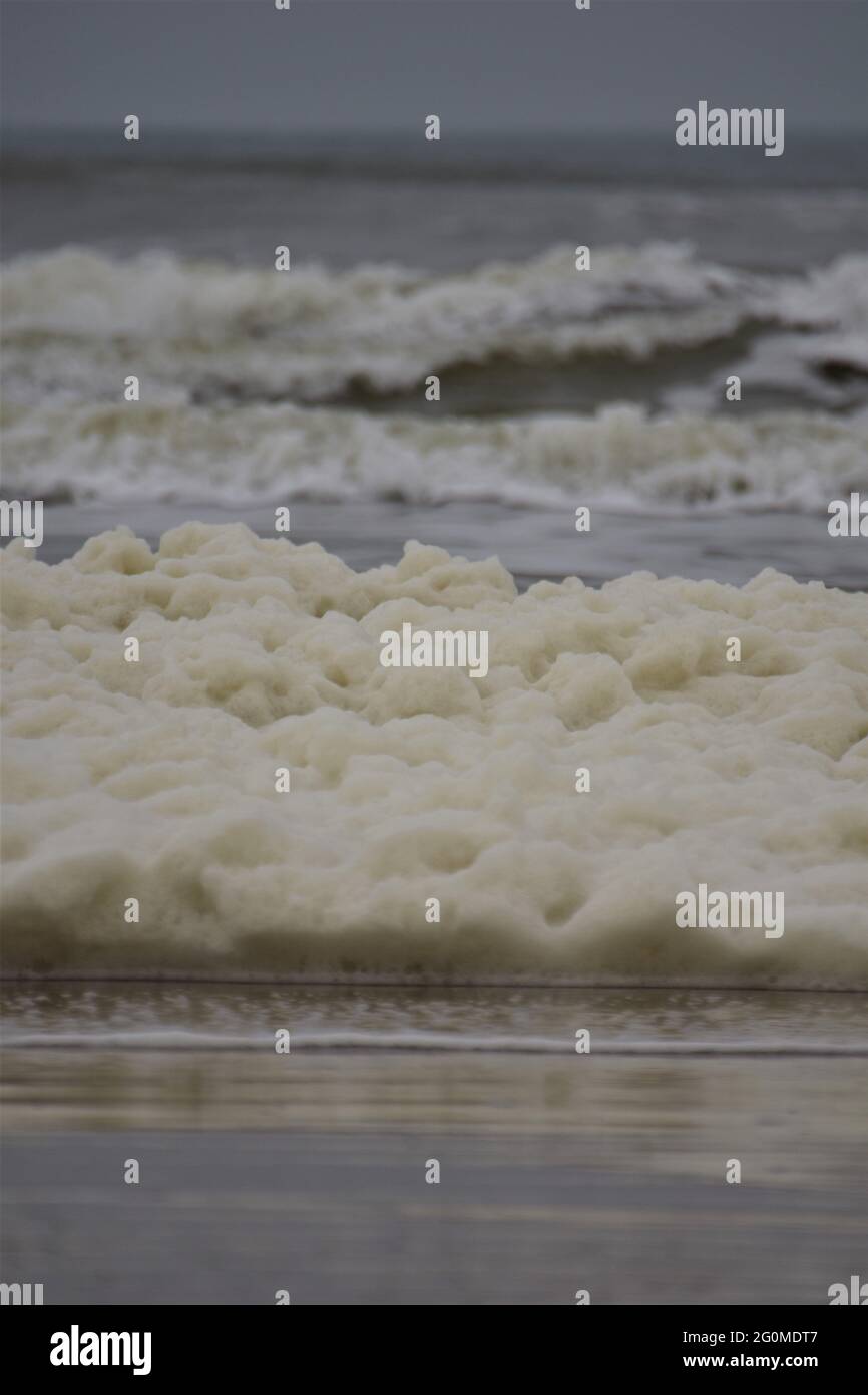 Die Wellen und der Meeresschaum auf dem Strand des Nordens Meer an einem bewölkten Tag Stockfoto