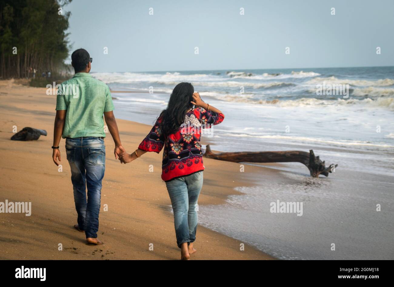 Paar, das am Sandstrand mit der Hand des anderen läuft und das natürliche Meeresbild einsaugend, wird im kochi kerala india aufgenommen und zeigt die Liebe Stockfoto