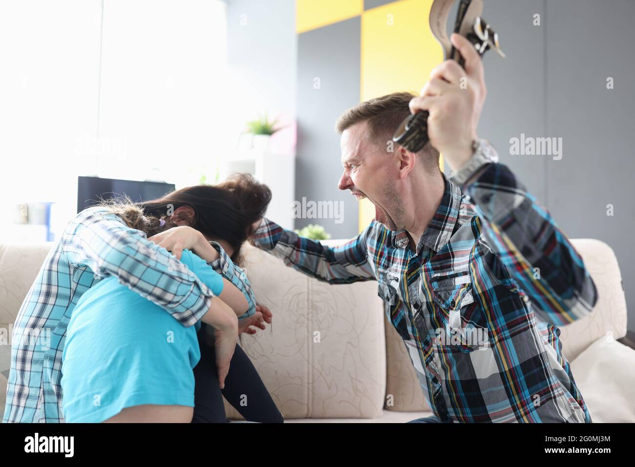 Wütender Mann schreit seine Frau und sein Kind an, die Gürtel in der Hand halten Stockfoto