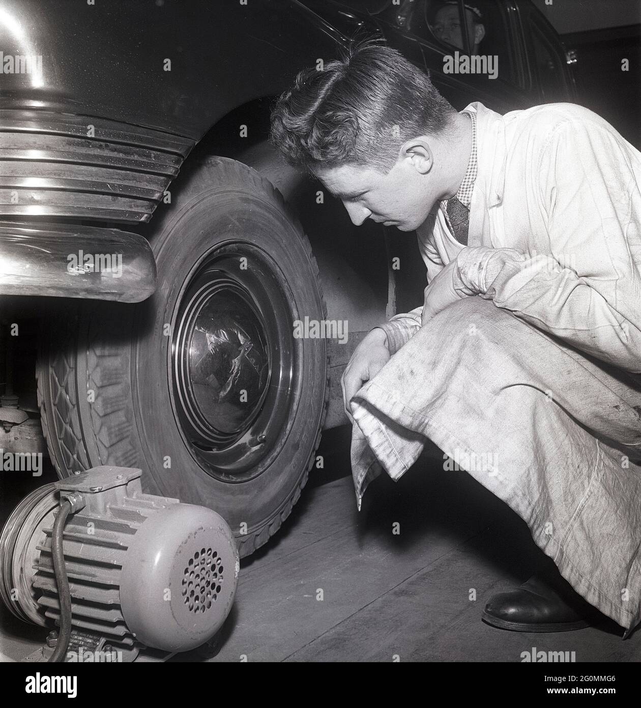 Ein oldtimer in einer alten garage mit einem mechaniker, der daran  arbeitet, und herum verstreuten werkzeugen