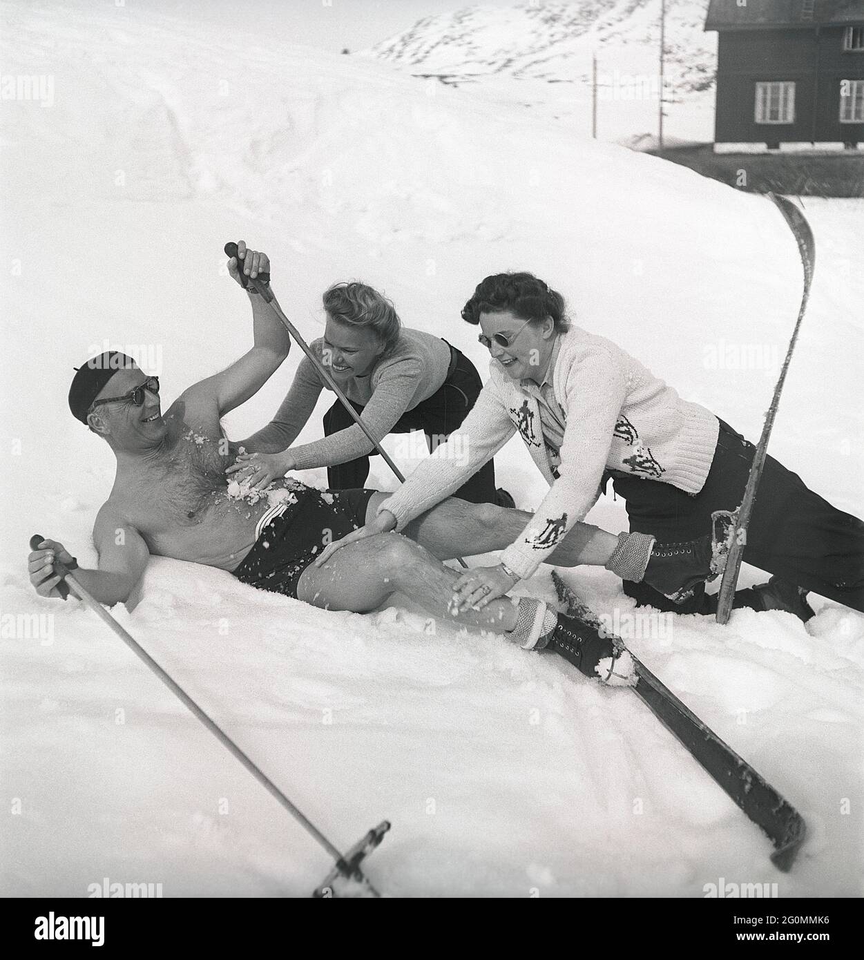 Winter in den 1940er Jahren. Der Frühling in den verschneiten schwedischen Bergen kann warm und sonnig sein, deshalb trägt er Badehosen. Er scheint auch etwas Abkühlung zu benötigen und bekommt dabei Hilfe von zwei Frauen, die ihn mit Schnee reiben. Alles hat Spaß gemacht. Schweden 1944 Ref. K9-6 Stockfoto