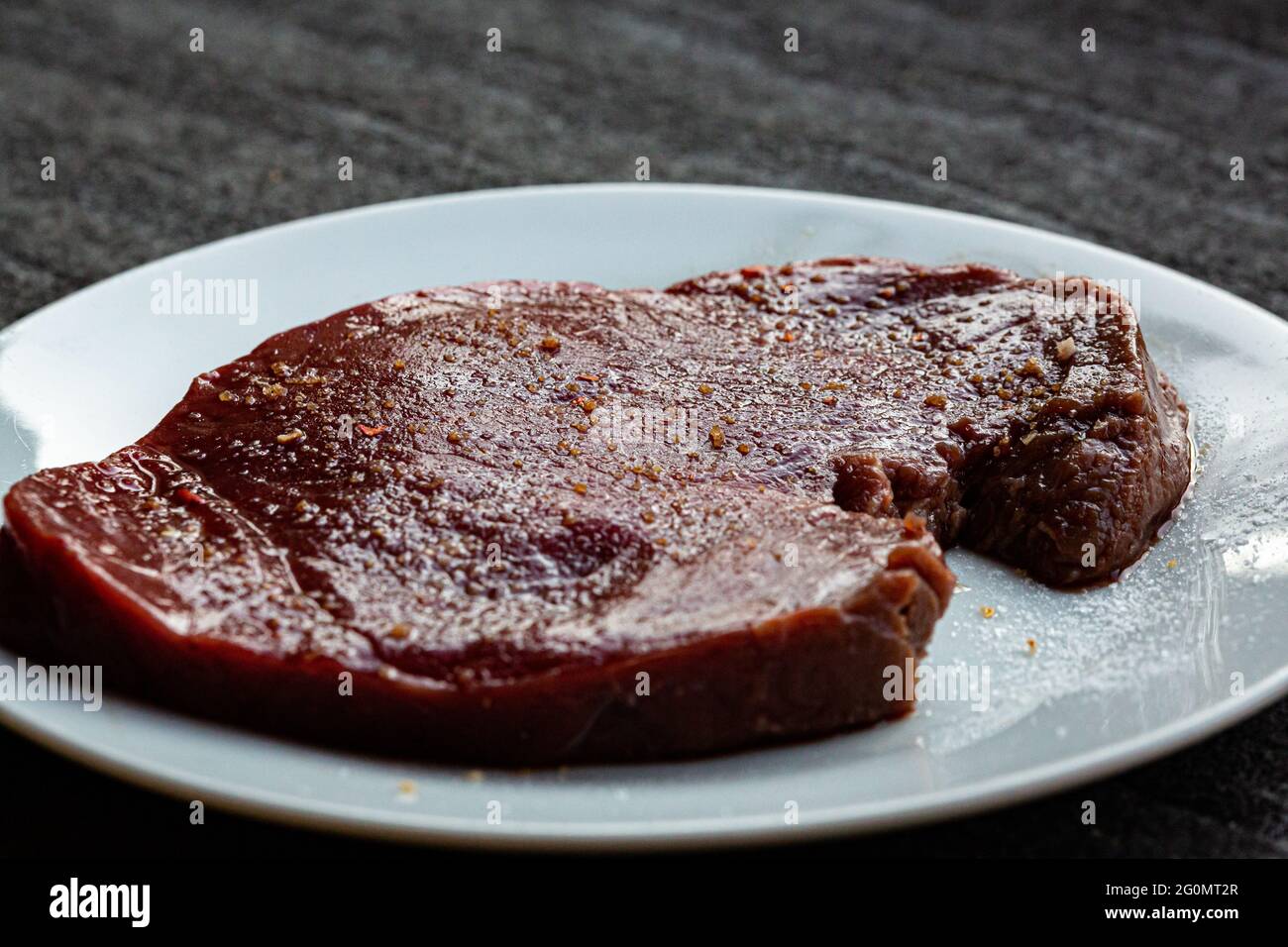Rohes, gewürztes und gesalzenes Steak, das vor dem Kochen ruht Stockfoto