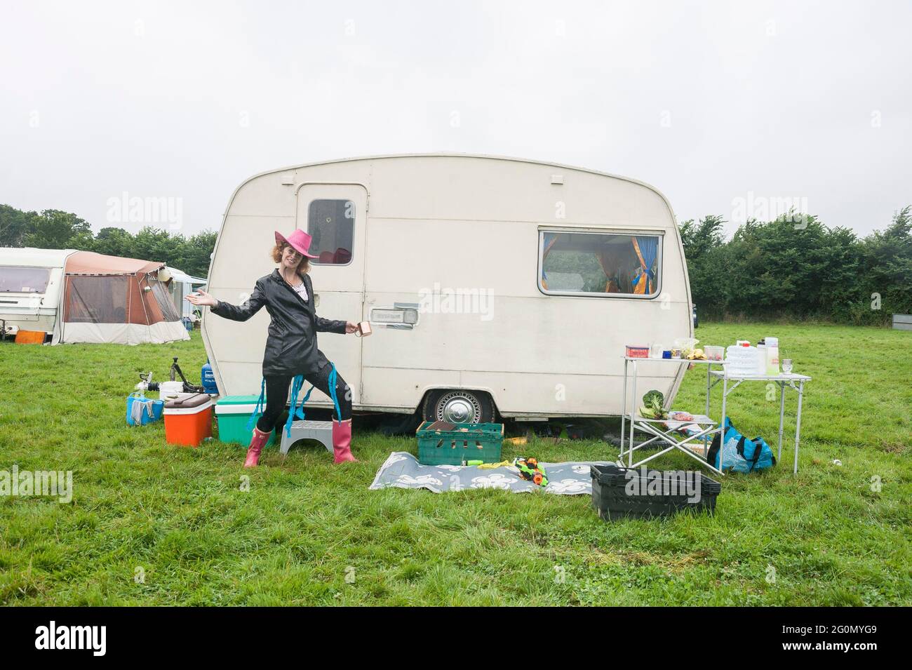 Vor einem Wohnwagen / Wohnmobil auf einem Fest auf einem Feld stehen. Stockfoto