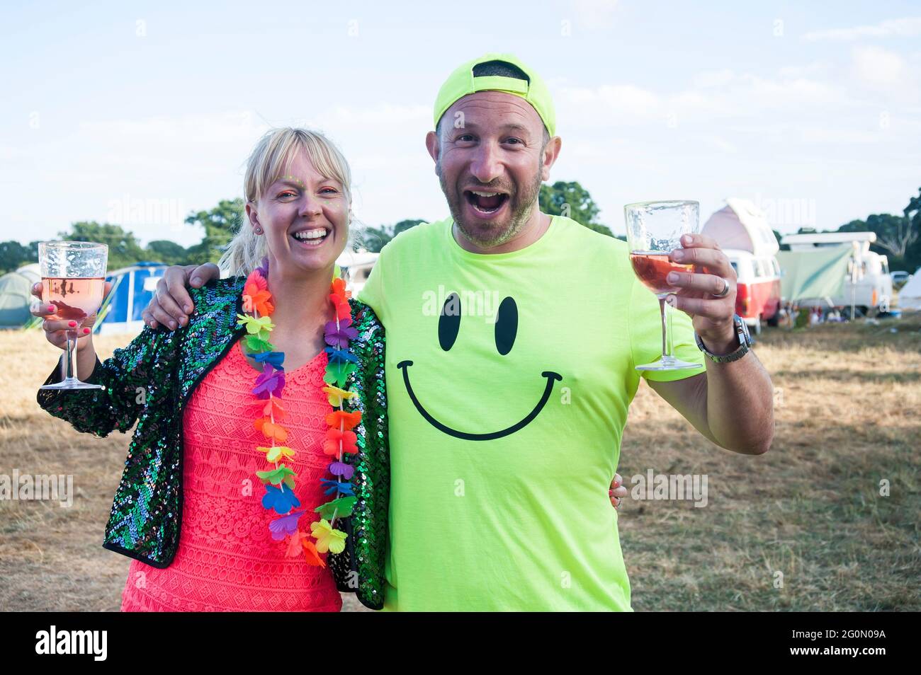 Eine Gruppe von Freunden und Menschen in Neon gekleidet bei einem Sommerfest auf einem Feld. Stockfoto