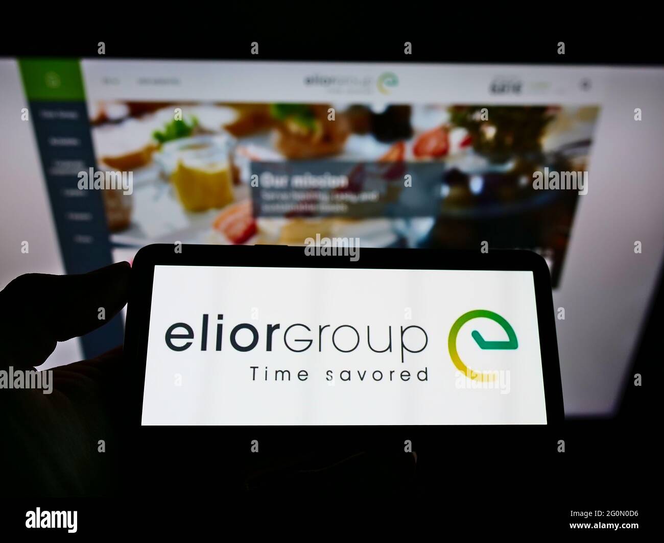Person, die das Smartphone mit dem Logo des französischen Catering-Unternehmens Elior Group SA auf dem Bildschirm vor der Website hält. Konzentrieren Sie sich auf die Telefonanzeige. Stockfoto