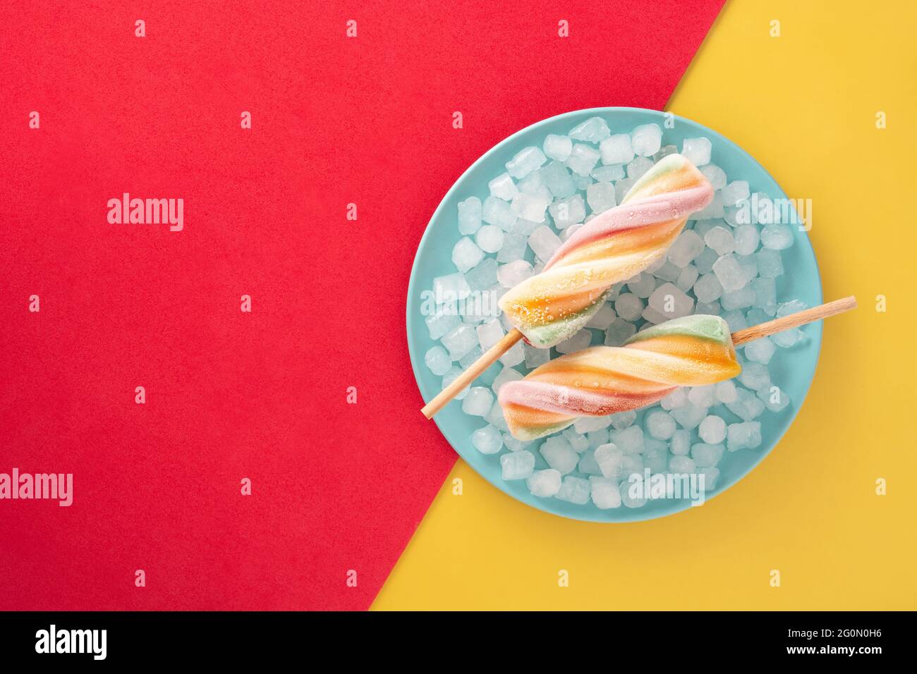 Spirale bunte Eiszapfen auf rotem und gelbem Hintergrund Stockfoto