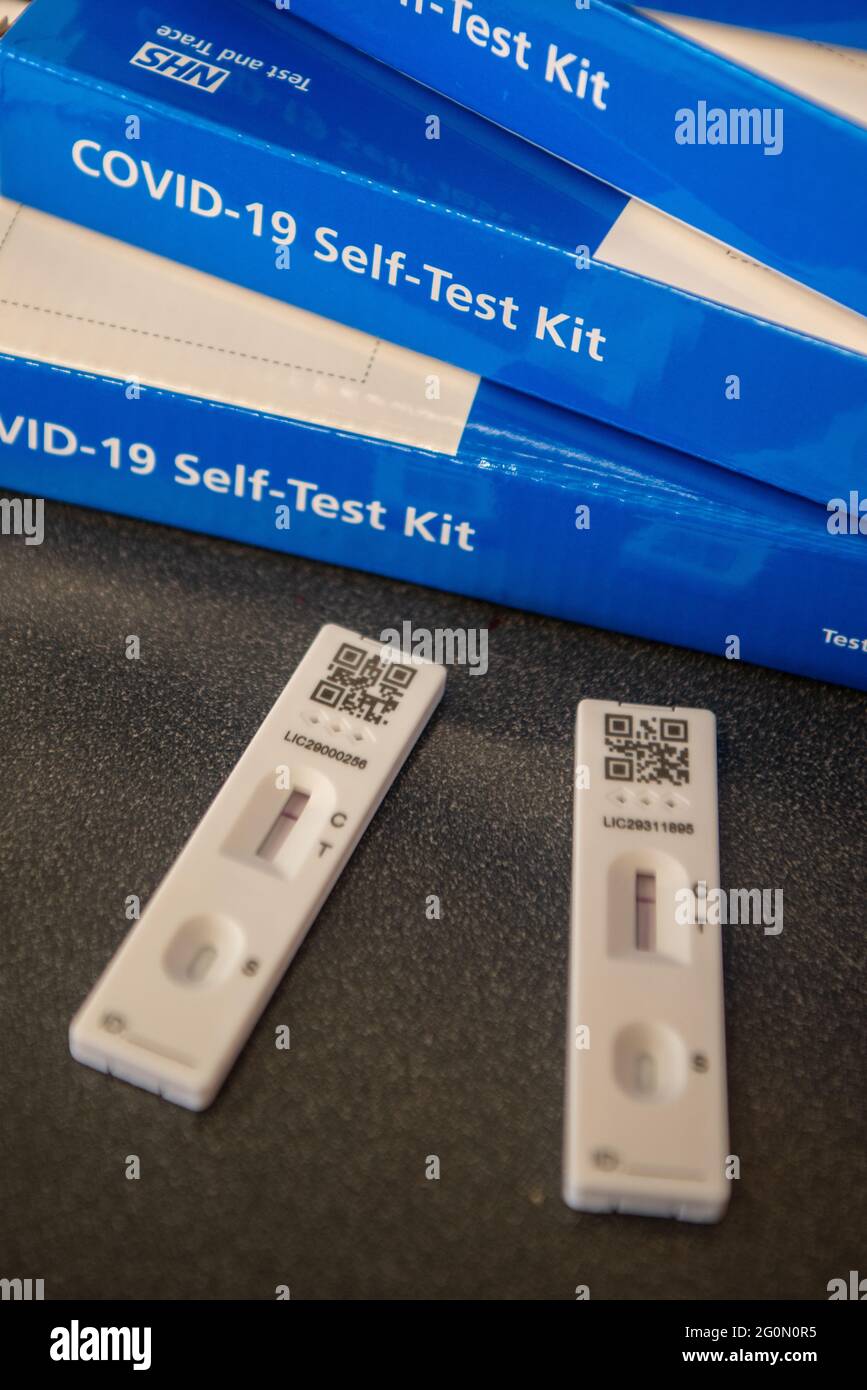 COVID-19 Selbsttestkits, gestapelt auf einem Tisch. Die Seite des blauen COVID-Testkits ist deutlich sichtbar Stockfoto