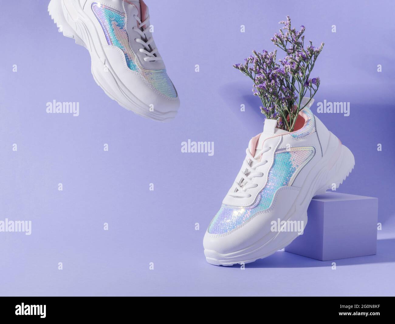 Weiße Sneakers mit Pailletten und Blumen auf violettem Hintergrund mit  geometrischem Würfelpodium Stockfotografie - Alamy