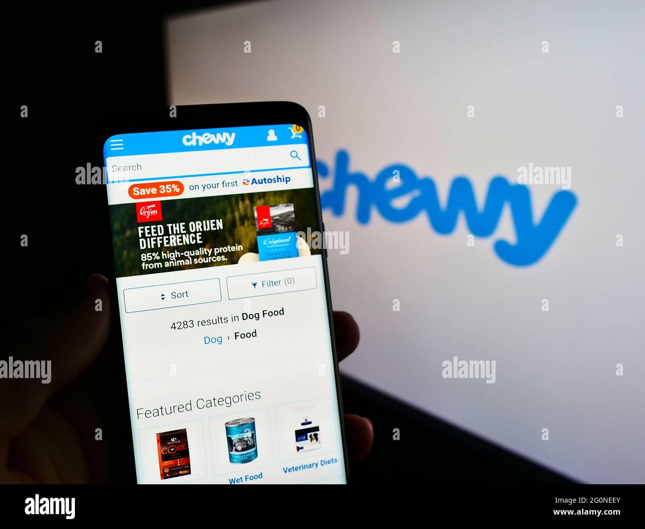 Person mit Smartphone und Website des US-amerikanischen Heimtiernahrung-Online-Einzelhandelsunternehmens Chewy Inc. Auf dem Bildschirm vor dem Logo. Konzentrieren Sie sich auf die Mitte des Telefondisplays. Stockfoto