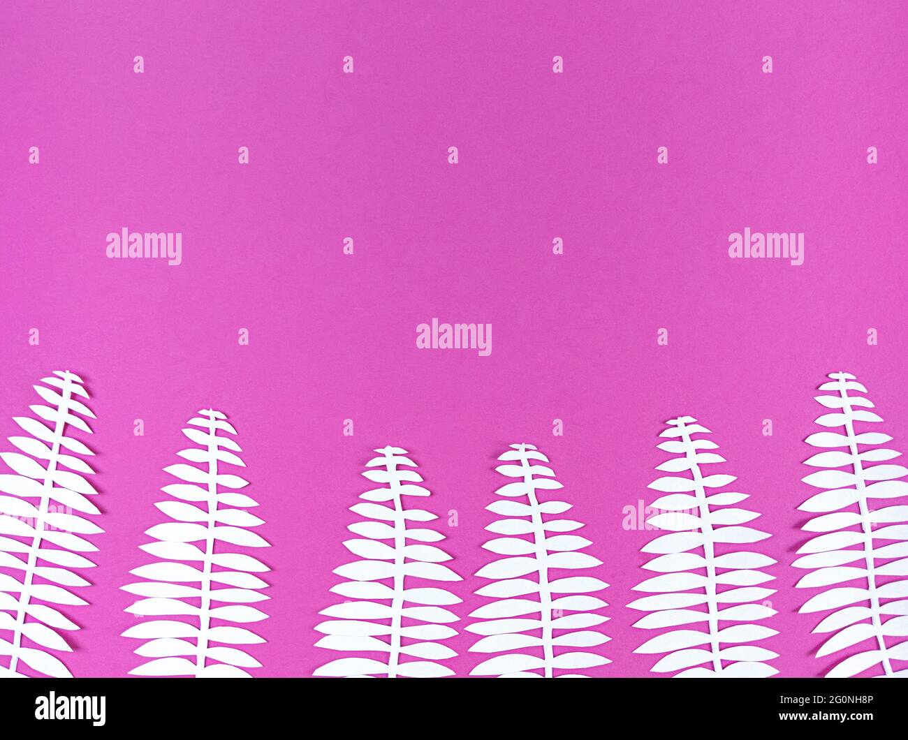 Weißes Papier geschnitten Blätter auf rosa Hintergrund. Stockfoto
