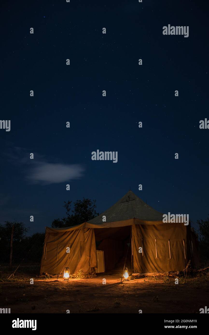 Ein von Laternen erleuchtetes Zelt unter dem afrikanischen Nachthimmel Stockfoto