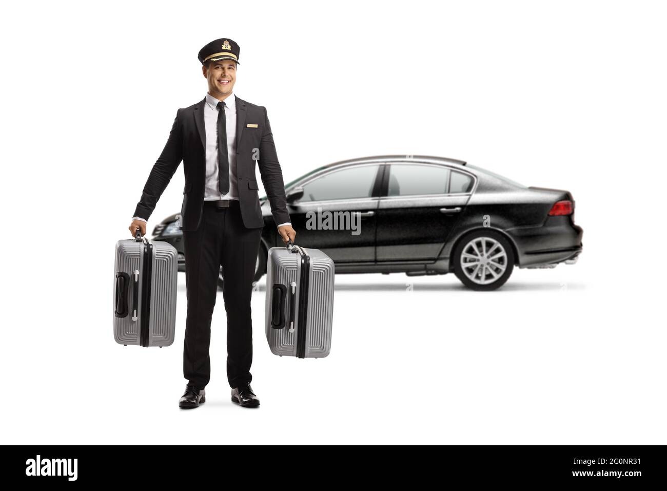In voller Länge Porträt eines Chauffeurs in einer Uniform, der Koffer vor einem schwarzen Auto trägt, isoliert auf weißem Hintergrund Stockfoto