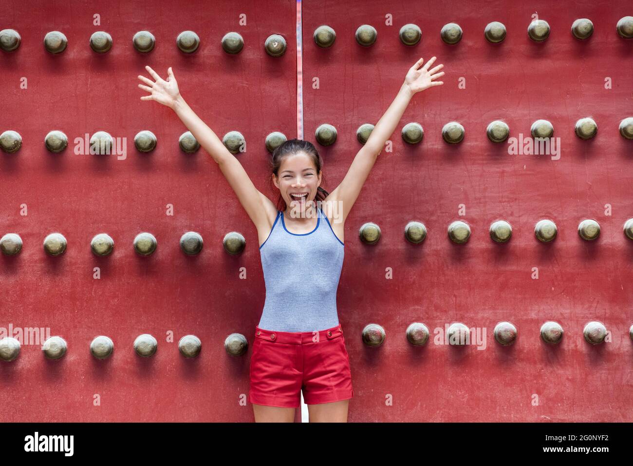 Viel Spaß in Asien. Aufgeregt Frau, die Freude mit den Armen auf Sommerurlaub durch alte hölzerne Tor in Tempel auf china Reise Urlaubsziel auszudrücken Stockfoto