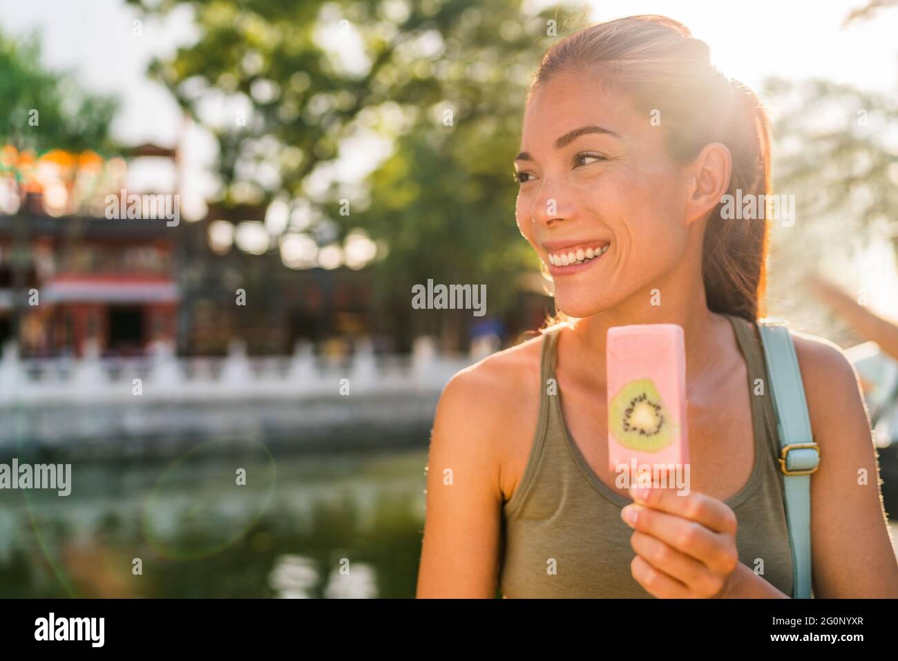 Glückliche asiatische Tourist Frau gesund essen genießen gefrorene Leckerbissen Snack im Sommer Park in Peking Hutongs, in der Nähe von Houhai See. Beliebtes städtisches Reiseziel Stockfoto