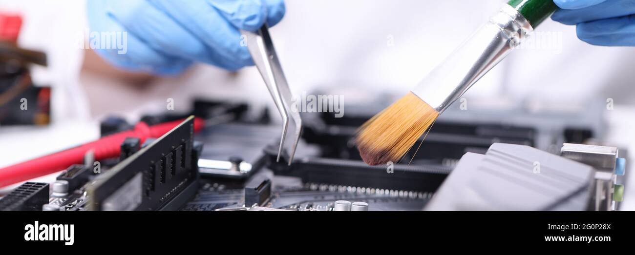 Handschuhen Handyman mit Pinsel und Pinzette Reparaturen Motherboard Stockfoto