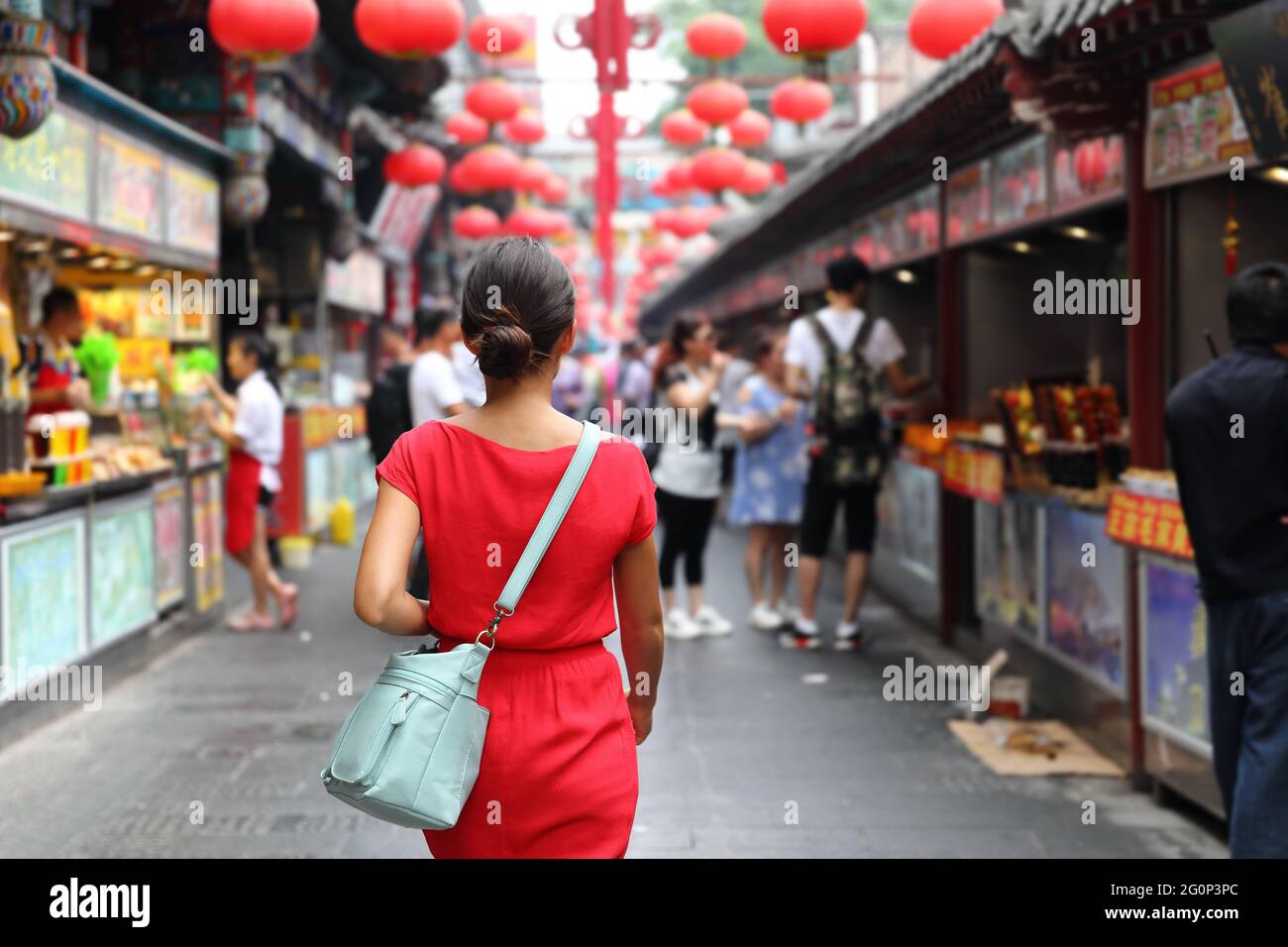 Frau, die auf chinatown unterwegs ist. Asiatische Mädchen auf Wangfujing Food Street während Asien Sommerferien. Traditionelle Peking Snacks werden Stockfoto