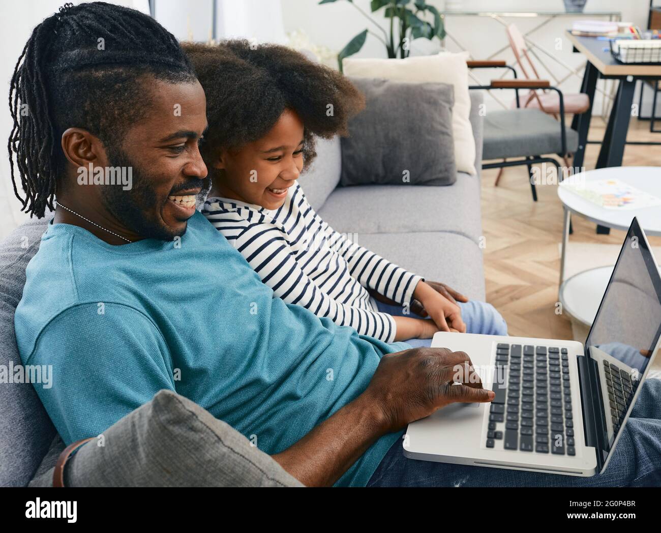 Vatertag. Vater und Tochter schauen sich gemeinsam den Laptop an und lachen. Vaterschaft, glückliche Familie Stockfoto