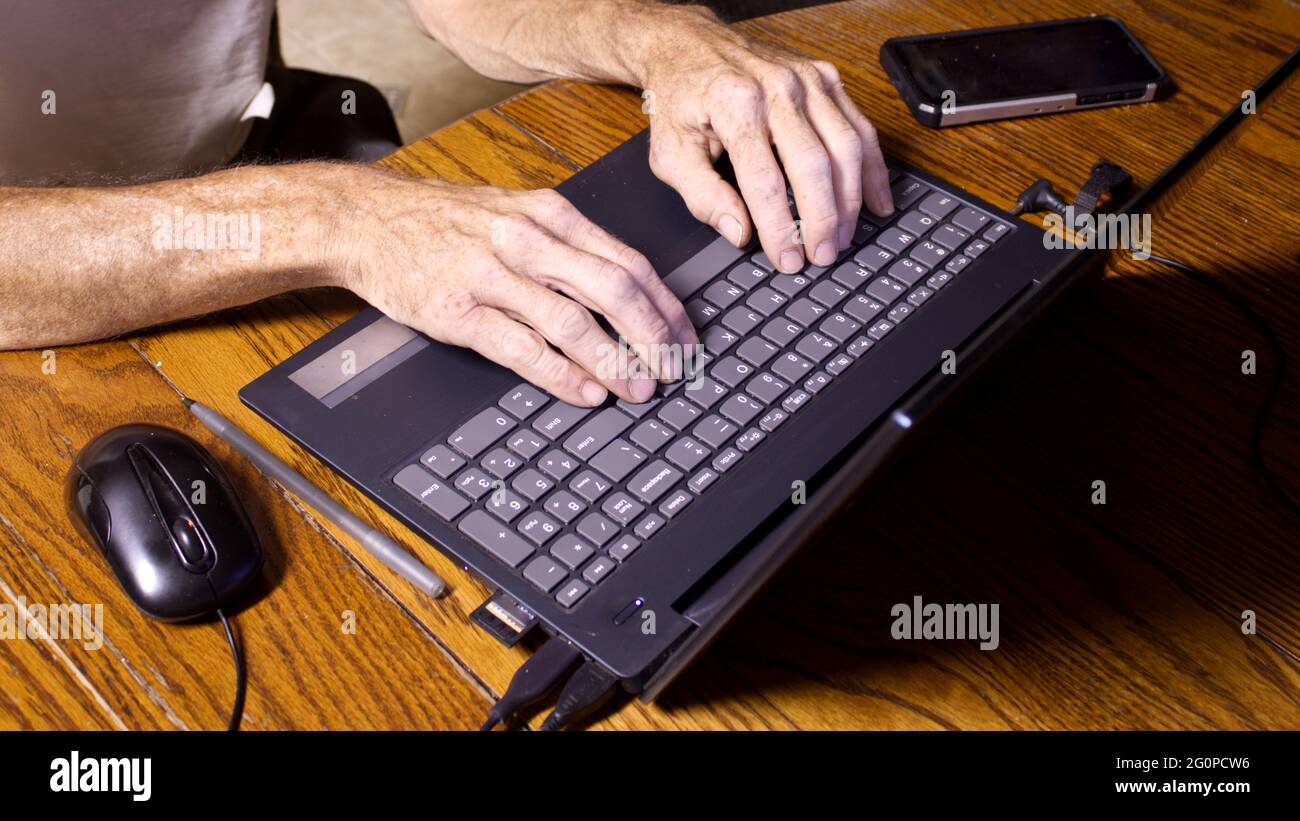 Eine Person tippt auf einer Tastatur auf einem Personal Computer Stockfoto