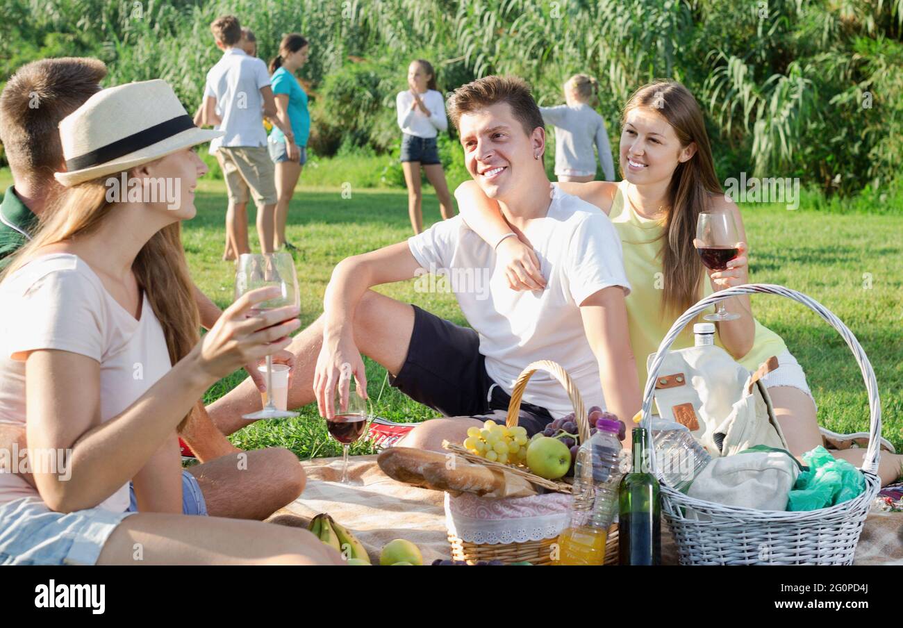 Glückliche junge Leute beim Picknick im Park und spielende Kinder Stockfoto