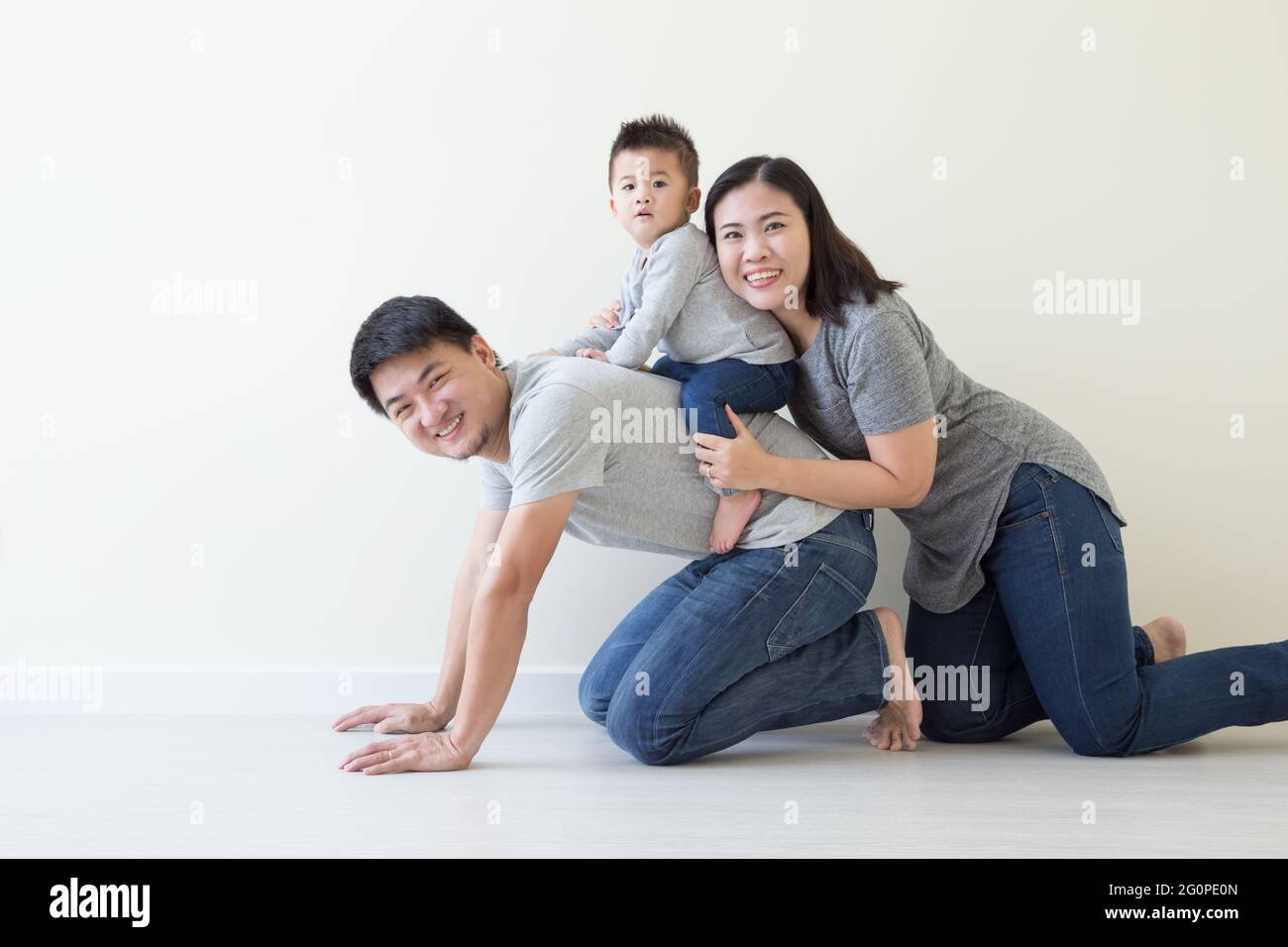 Glückliche Familie mit thailändischer und chinesischer Abstammung und einem kleinen Jungen, der sich auf dem Boden amüsieren kann Stockfoto