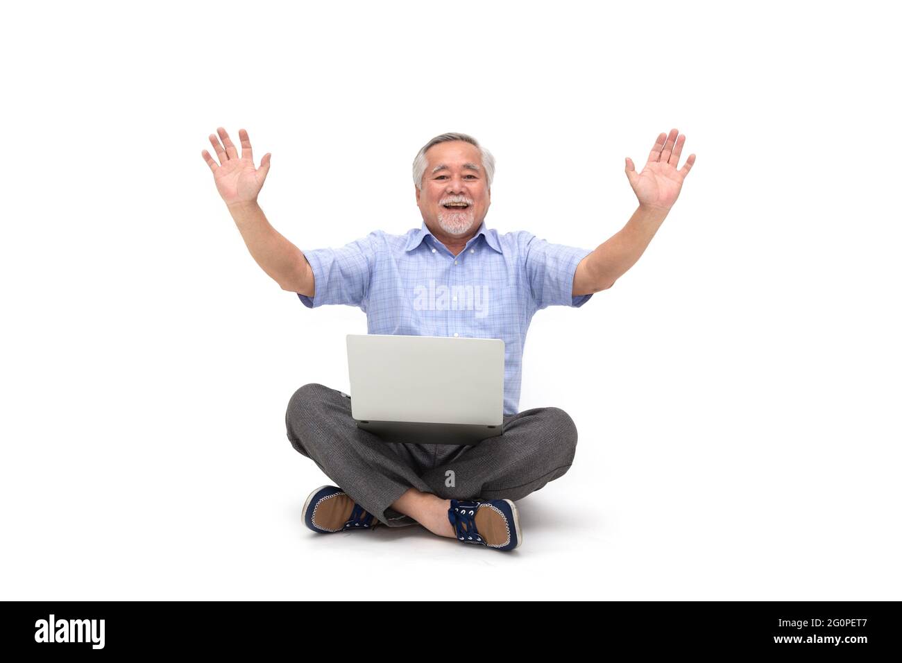 Asiatischer älterer Mann feiert Erfolg und übergibt sich und sitzt auf dem Boden mit Laptop isoliert auf weißem Hintergrund Stockfoto