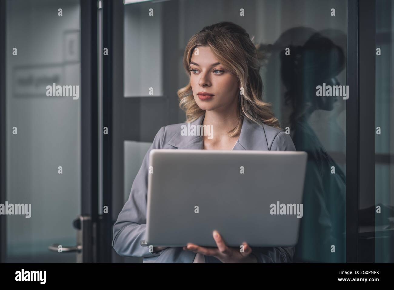 Junge Geschäftsfrau, die mit einem offenen Laptop steht Stockfoto