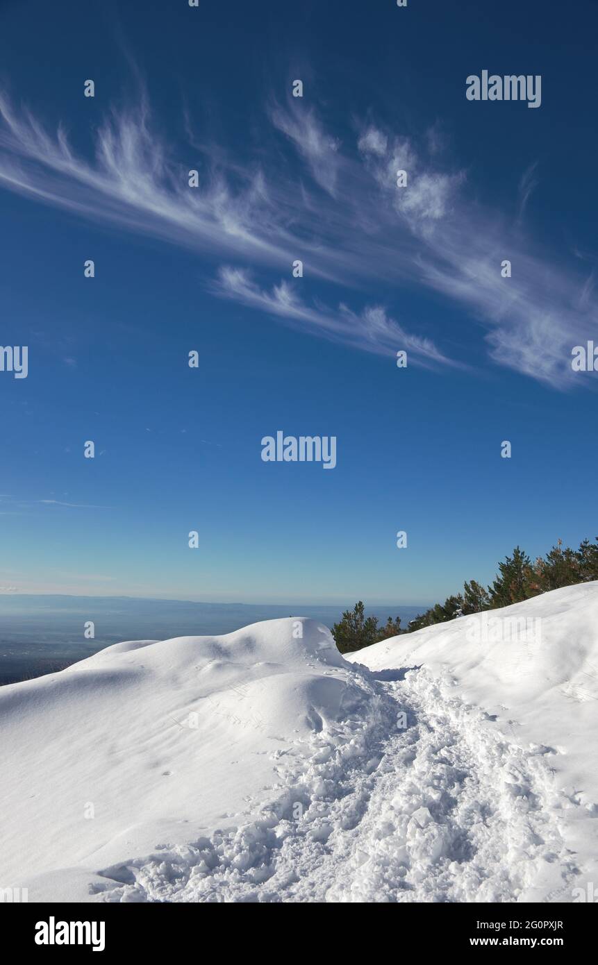 Ein Winter schönen Tag im Freien in der Natur Siziliens, Fußabdrücke von Wanderern auf schneebedeckten Weg gegen blauen Himmel mit weißen Wolken im Ätna Park Stockfoto