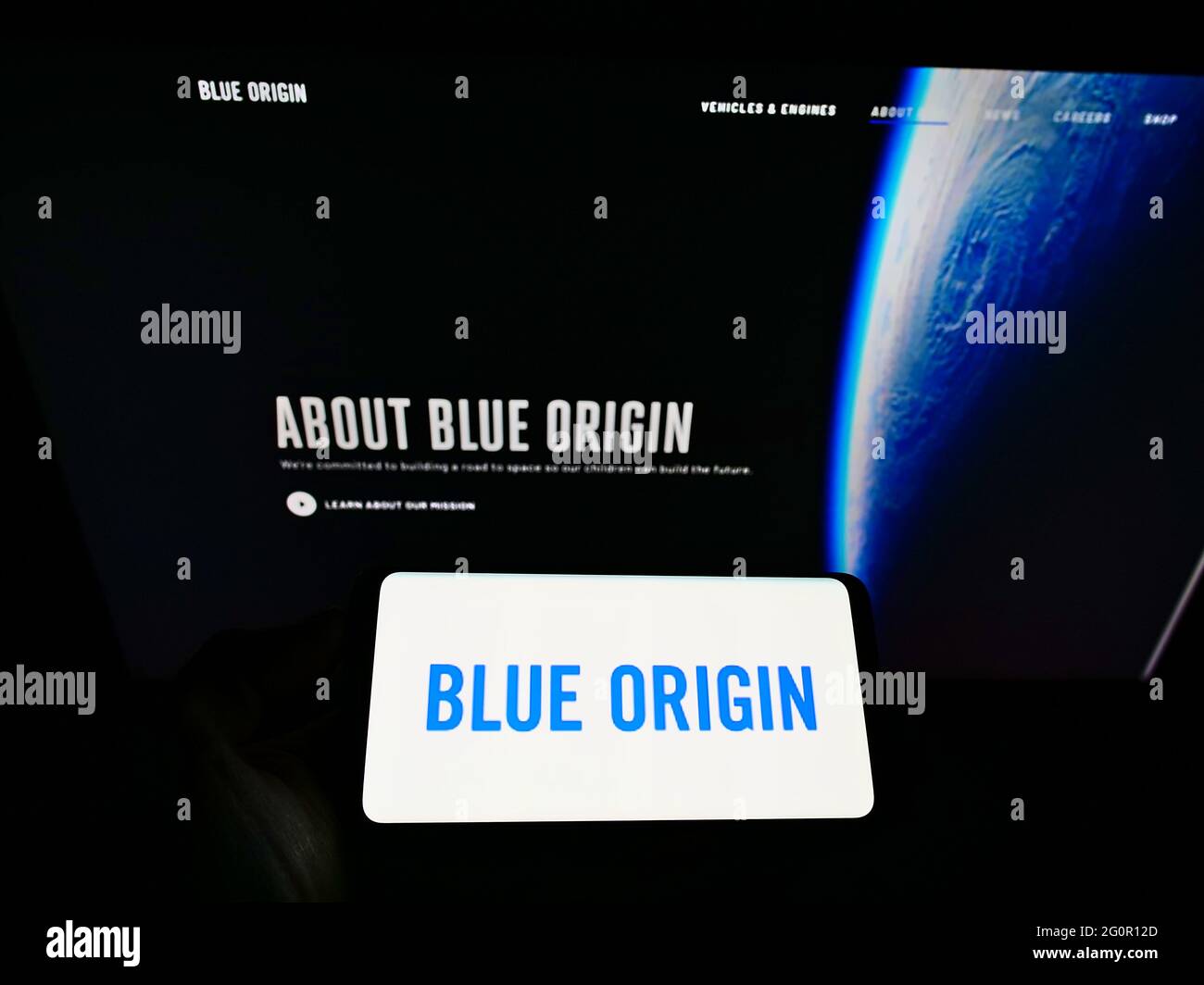 Person, die Smartphone mit dem Logo des US-Luftfahrtunternehmens Blue Origin LLC auf dem Bildschirm vor der Website hält. Konzentrieren Sie sich auf die Telefonanzeige. Stockfoto
