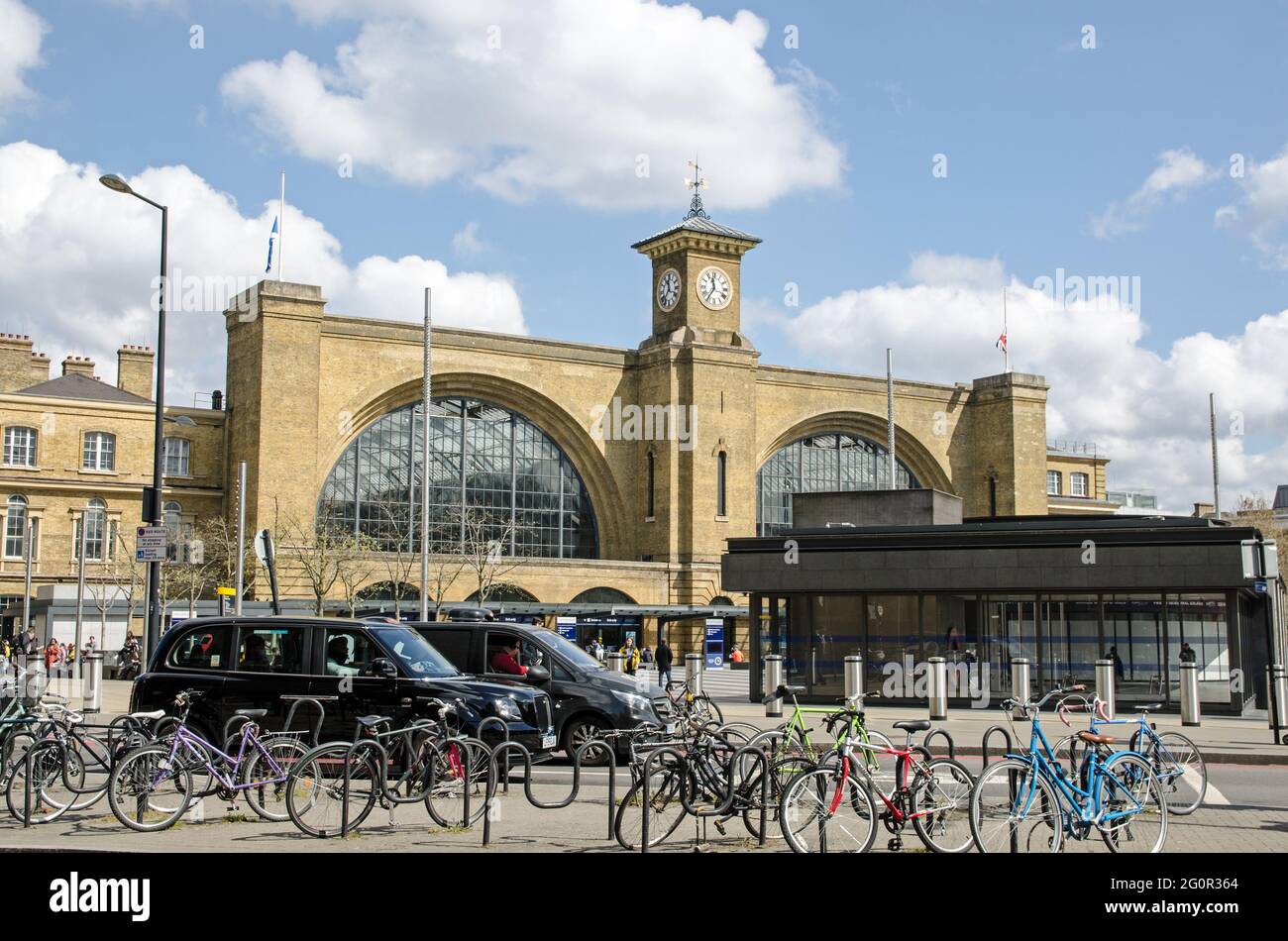 London, Großbritannien - 16. April 2021: Personen, Fahrräder und Taxis vor der Kings Cross-Endstation im Zentrum von London. Züge Stockfoto
