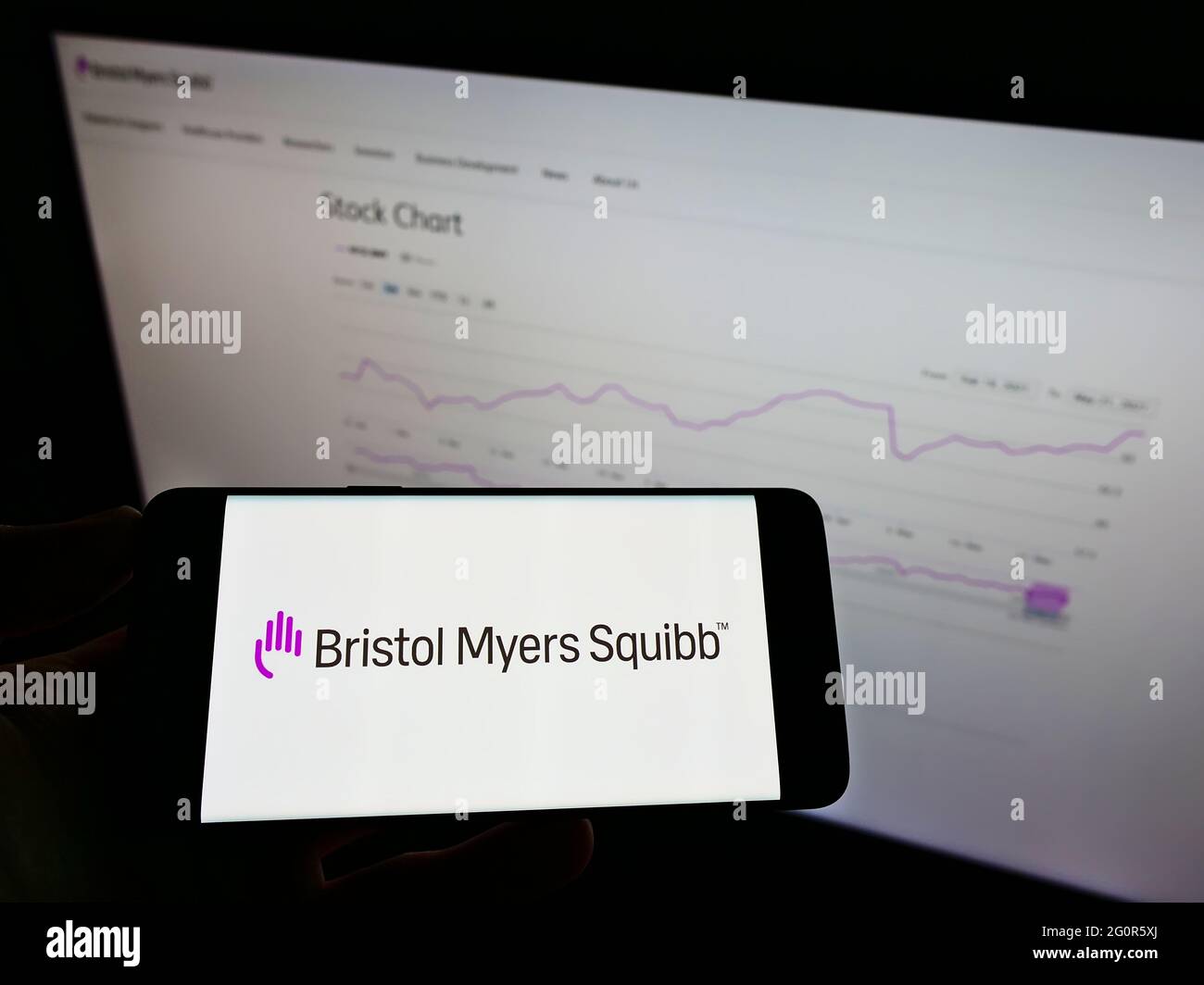 Person, die das Smartphone mit dem Logo des US-Pharmaunternehmens Bristol Myers Squibb (BMS) auf dem Bildschirm vor der Website hält. Konzentrieren Sie sich auf die Telefonanzeige. Stockfoto