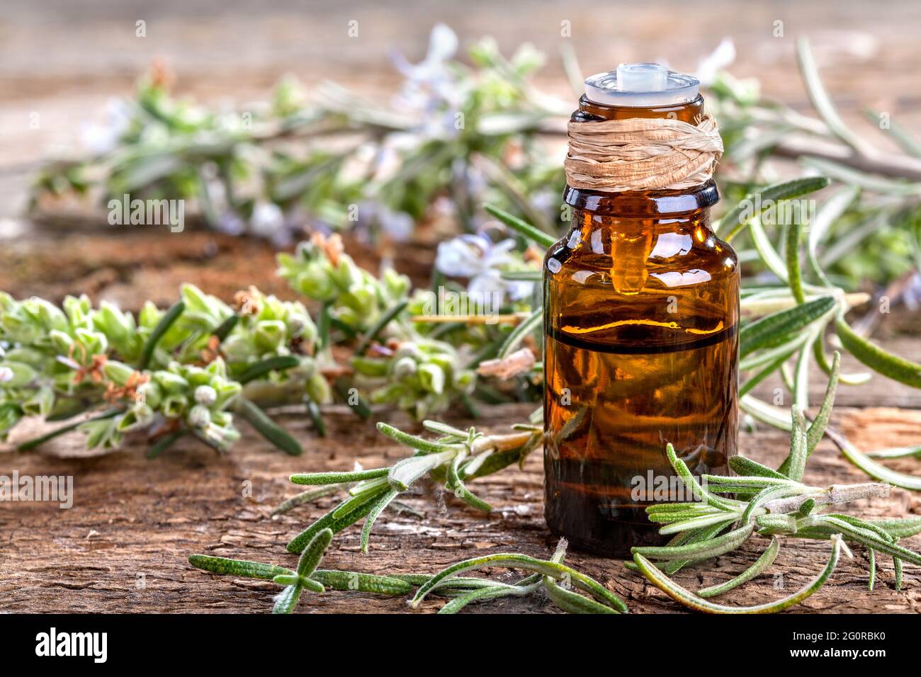 Ätherisches Öl aus Rosmarin auf rustikalem Tisch Stockfoto