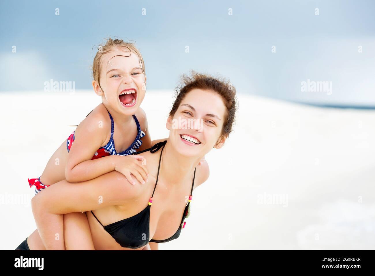 Glückliche Mutter und kleine Tochter, die sich im Sommerurlaub am Sandstrand auf den Malediven amüsieren. Familie am Strand Konzept. Stockfoto