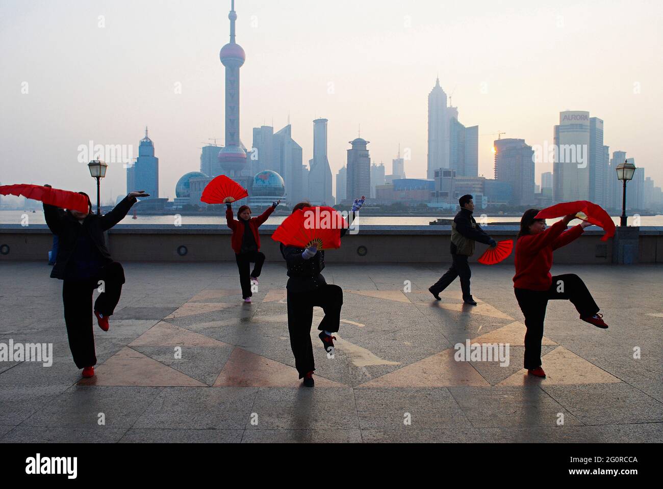 China. Shanghai. Chinesische Frauen tanzen jeden Morgen mit roten Fans auf dem bund in Shanghai zum Training. Stockfoto