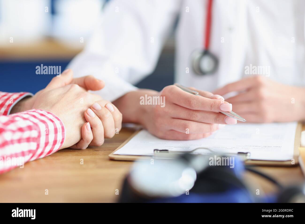 Der Arzt sieht den Patienten und schreibt medizinische Indikatoren auf die Karte Stockfoto