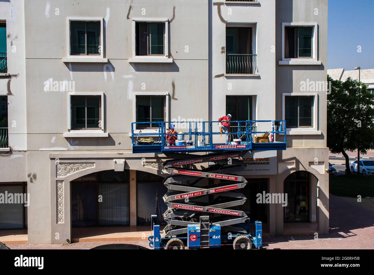 Dubai, VAE - Aufnahme eines in der Höhe arbeitenden Wartungspersonal, das die Fassade des Gebäudes im internationalen Stadtbezirk repariert. Stockfoto